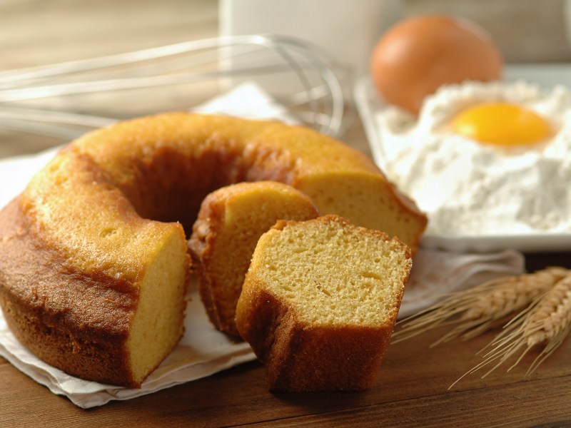 Italienischer Frühstückskuchen auf weißer Serviette und Backzutaten im Hintergrund