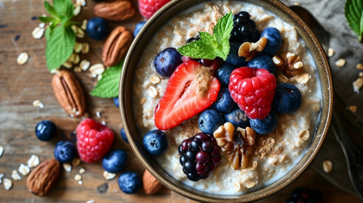 Schüssel mit Porridge, verschiedenen Beeren und Nüssen