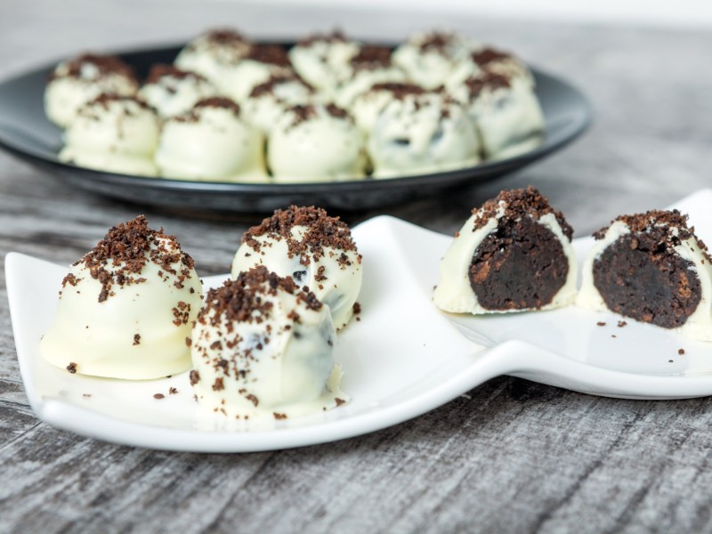 Weißer Teller mit Oreo-Pralinen und einem dunklen Teller Pralinen im Hintergrund