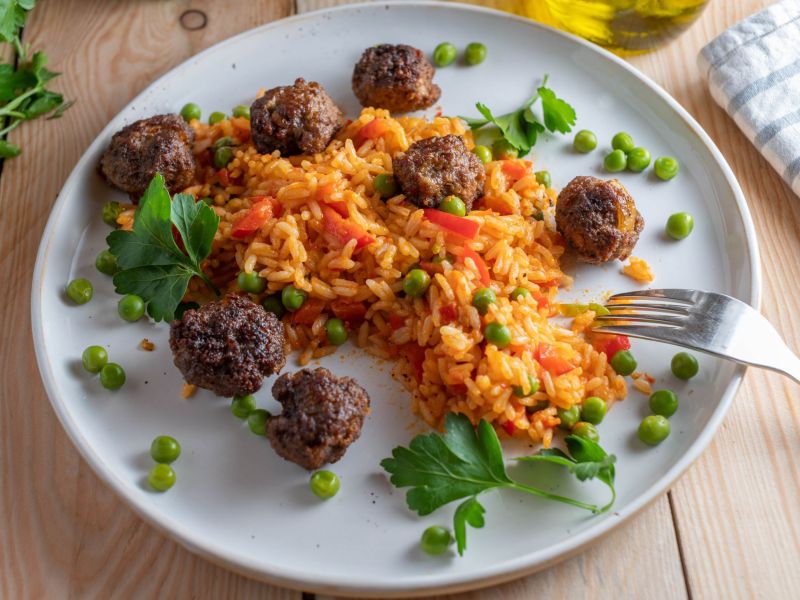 Paprika-Risotto mit Hackbällchen, angerichtet auf einem Teller.