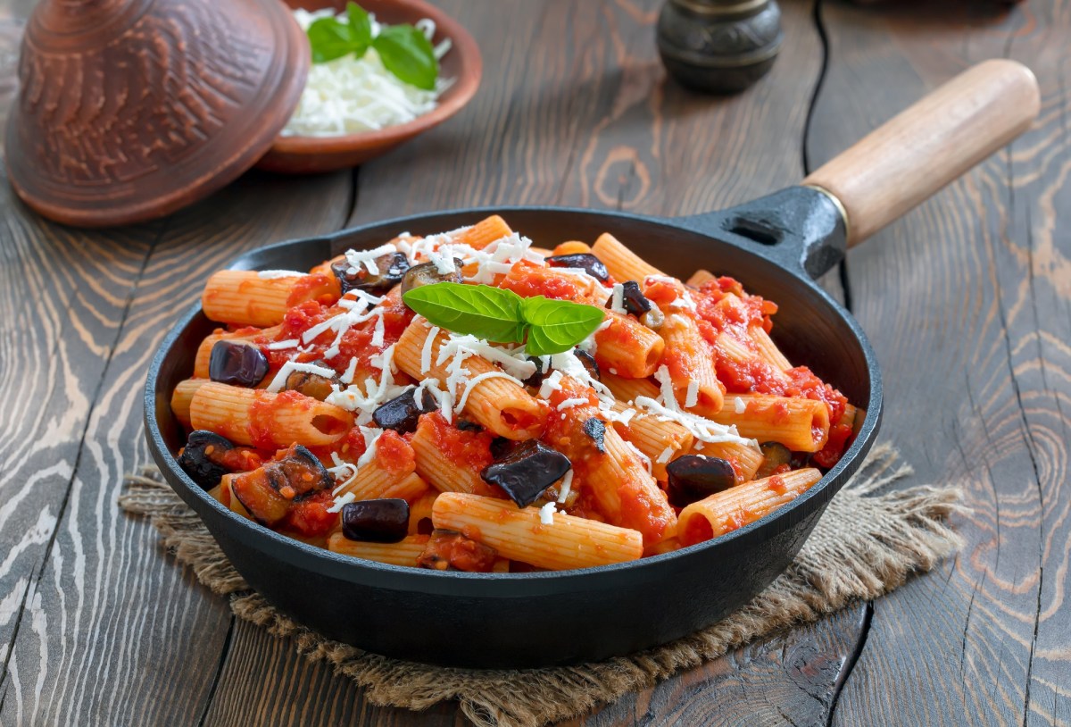 Pasta alla Norma in einer gusseisernen Pfanne mit Pecorino und Basilikum.