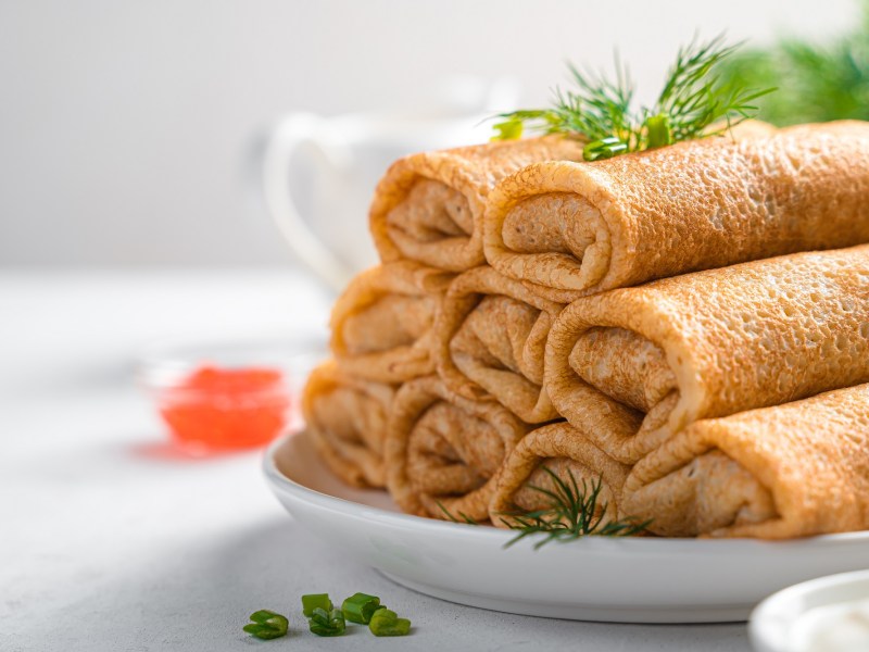 Ein Stapfel Pfannkuchen-Frischkäse-Röllchen auf einem Teller, Nahaufnahme.