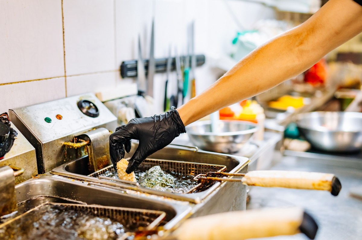 Ratgeber zum richtigen Frittieren: Eine Hand legt ein Stück Frittiergut in eine Fritteuse