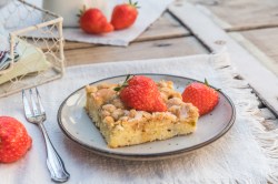 1 Stück Streuselkuchen mit Pudding garniert mit Erdbeeren auf einem Teller