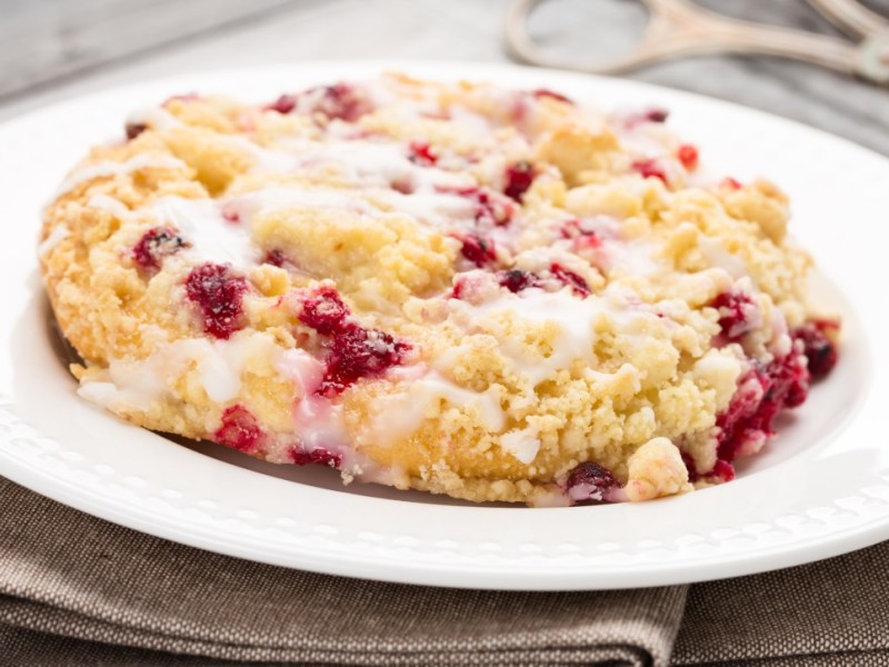 Eine Streuselschnecken mit Johannisbeeren auf einem Teller.