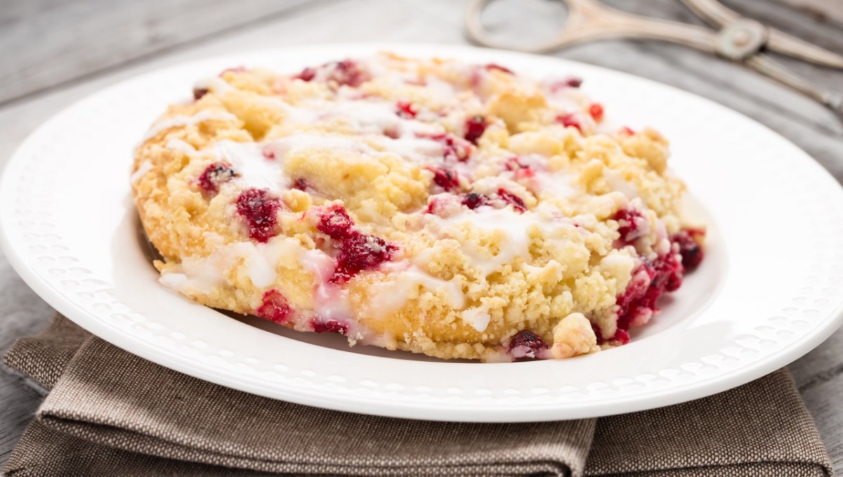 Eine Streuselschnecken mit Johannisbeeren auf einem Teller.