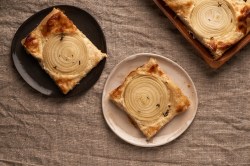 zwei Teller mit Zwiebel-Tartelettes auf braunem Leinentuch