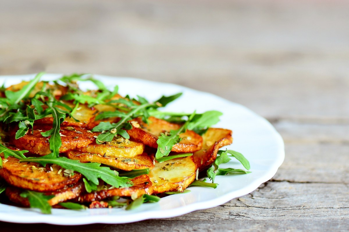 Ein Teller Bratkartoffeln mit Rucola und Knoblauch, Nahaufnahme