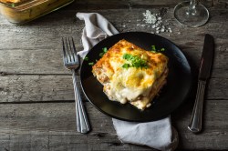 Teller mit Ei-Lasagne auf Holztisch