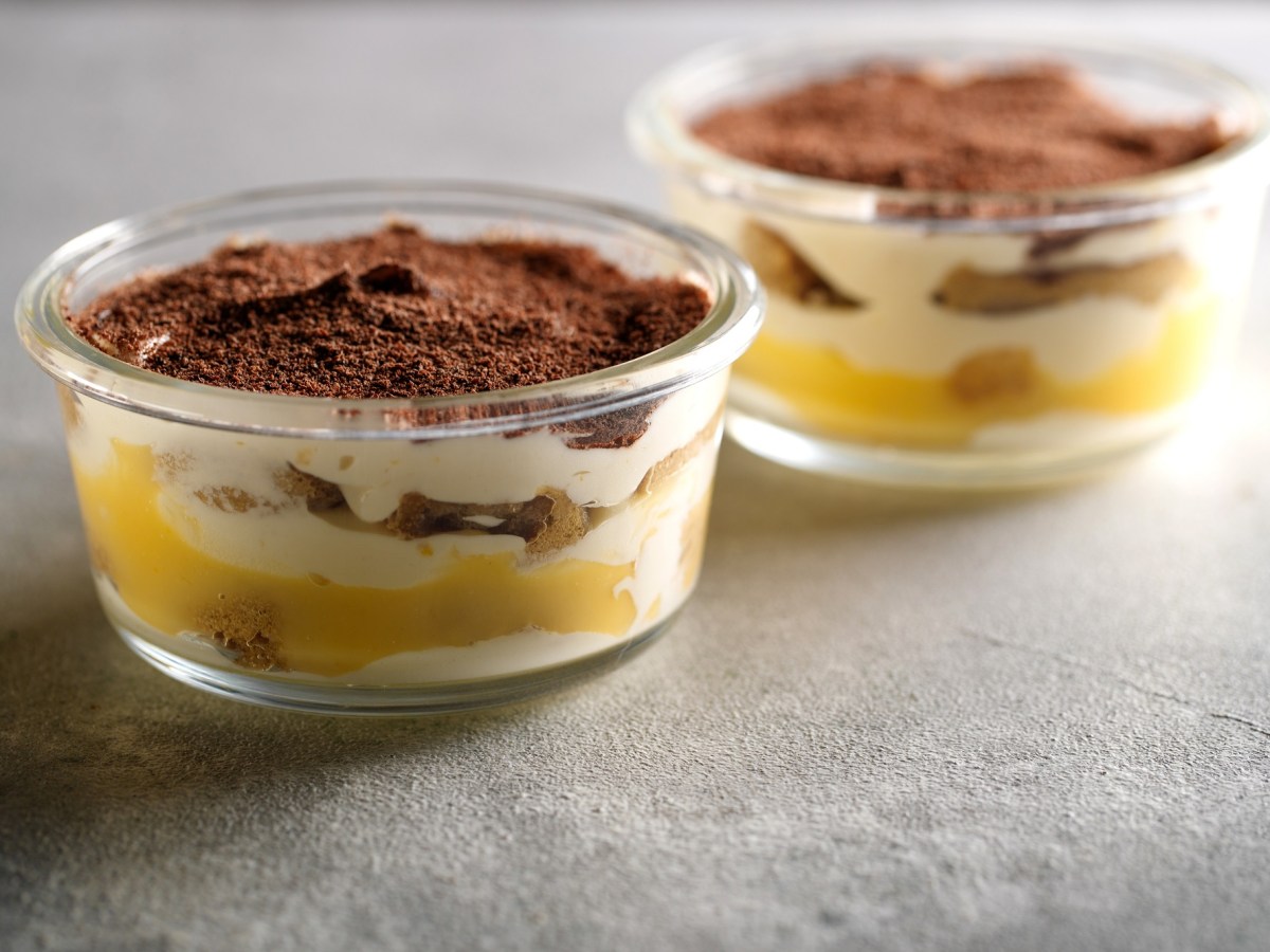 Zwei Gläser mit Eierlikör-Tiramisu auf dunklem Untergrund.