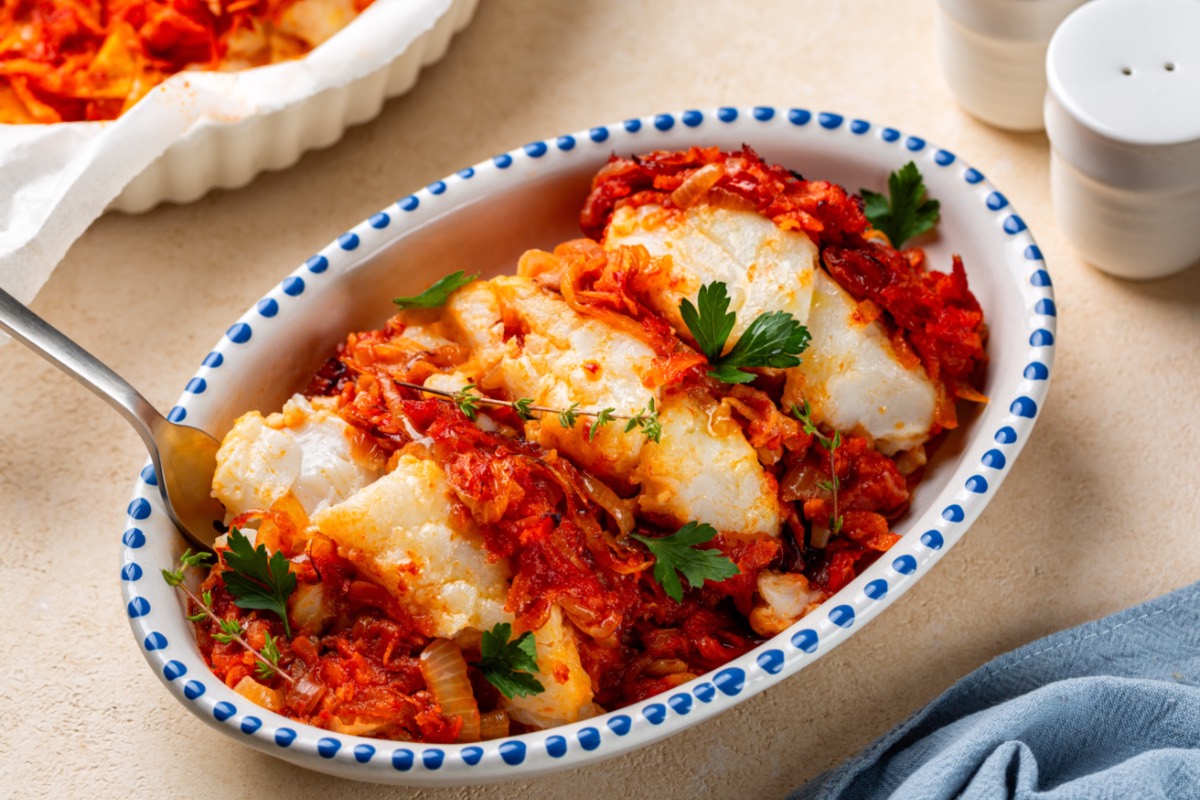 Griechischer Fischauflauf mit Tomaten und Feta in Auflaufform in der Draufsicht.