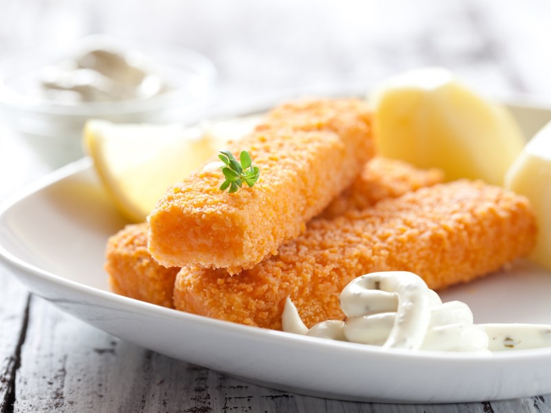 Fischstäbchen Stiftung Warentest: 3 Fischstäbchen auf einem Teller mit Remoulade und Zitronenspalten.