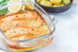 Auflaufform mit Lachs-Sahne-Gratin auf hellem Untergrund