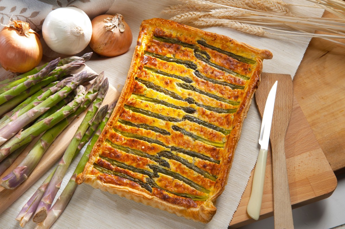 Blätterteigtarte mit Spargel und Parmesan auf einem dekorierten Tisch.