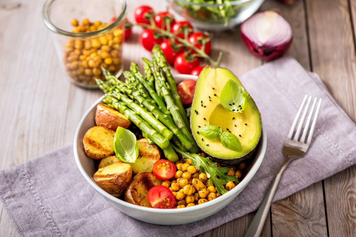 Schüssel mit Buddha Bowl mit Spargel, Gabe daneben.