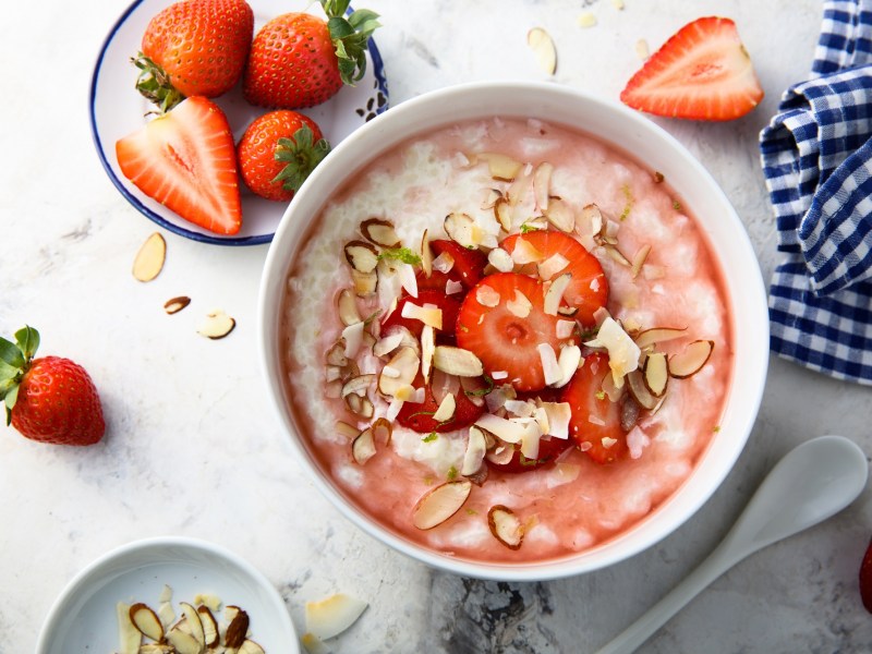 Schüssel mit Erdbeer-Mandel-Porridge und Erdbeeren daneben