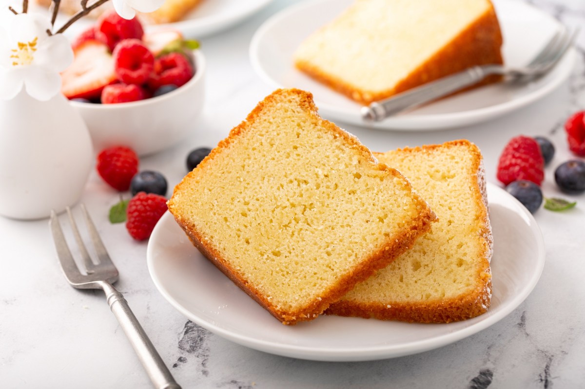 Zwei Stücke französischer Joghurtkuchen auf einem weißen Teller. Daneben liegen verschiedene Beeren.