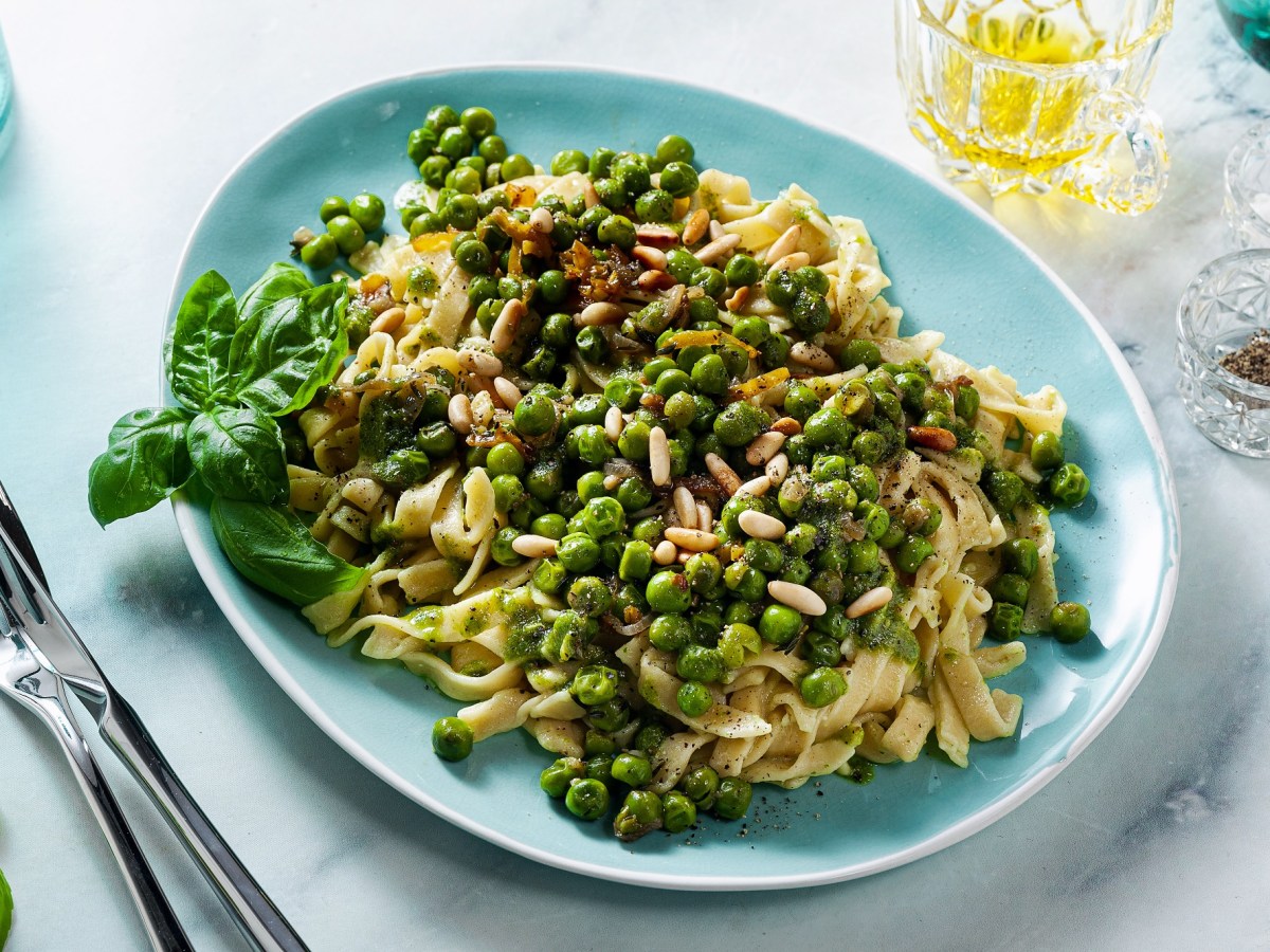 Blauer Teller mit Frühlingspasta mit grünen Erbsen.