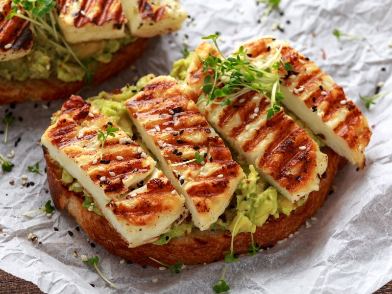 Ein Halloumi-Brot mit Avocado, dekoriert mit Kresse und Sesam.