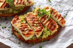 Ein Halloumi-Brot mit Avocado, dekoriert mit Kresse und Sesam.