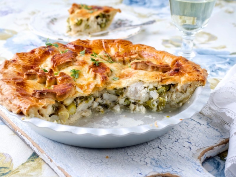 Ein angeschnittene Pastilla mit Fisch und grünem Spargel auf einem Teller.