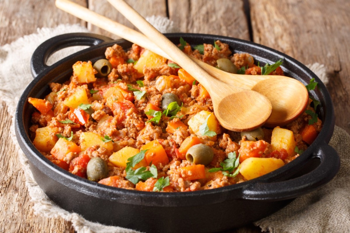 Picadillo, mexikanische Hackfleischpfanne, auf der zwei Holzlöffel liegen.