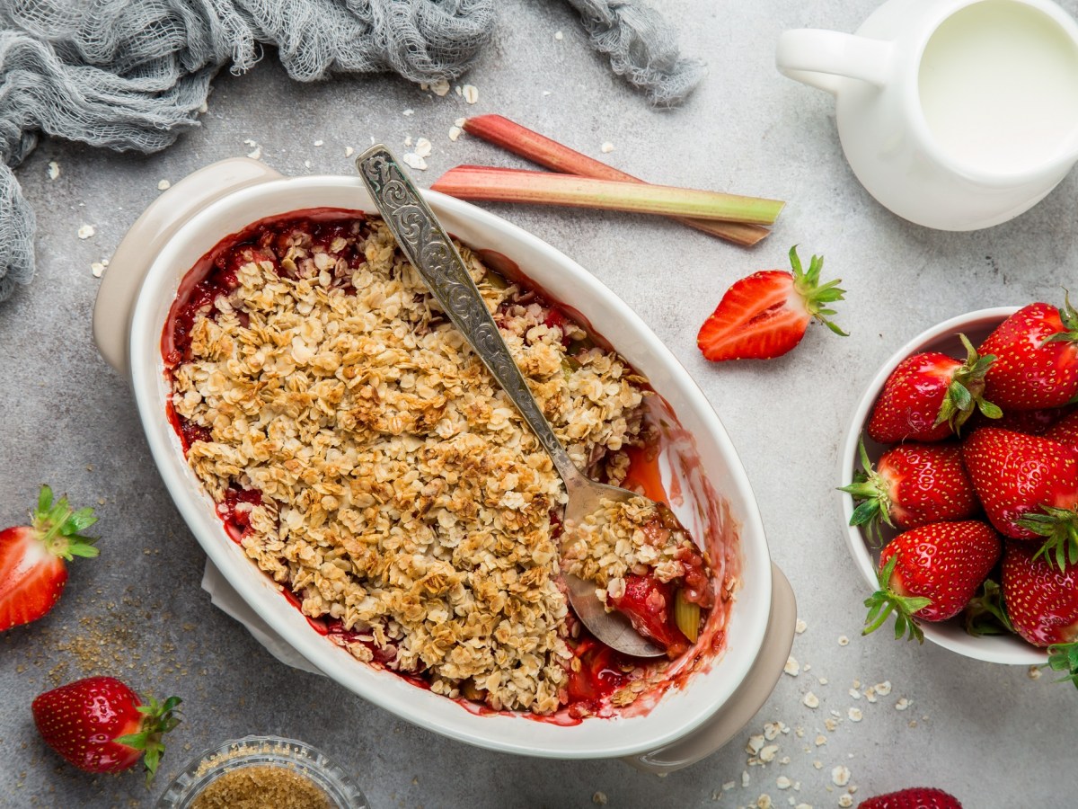 Ein Rhabarber-Erdbeer-Crumble in einer Auflaufform, dekoriert mit Erdbeeren.