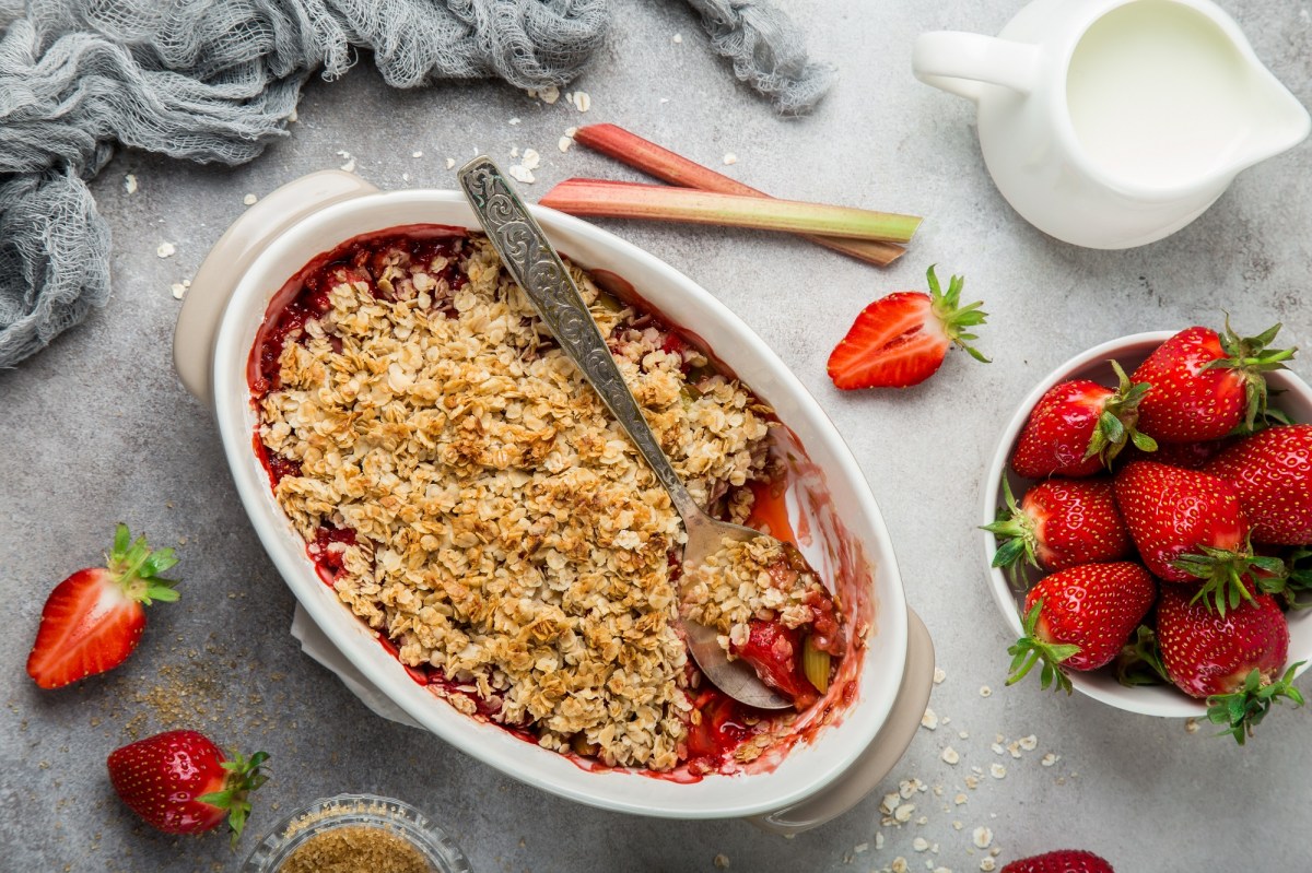 Ein Rhabarber-Erdbeer-Crumble in einer Auflaufform, dekoriert mit Erdbeeren.