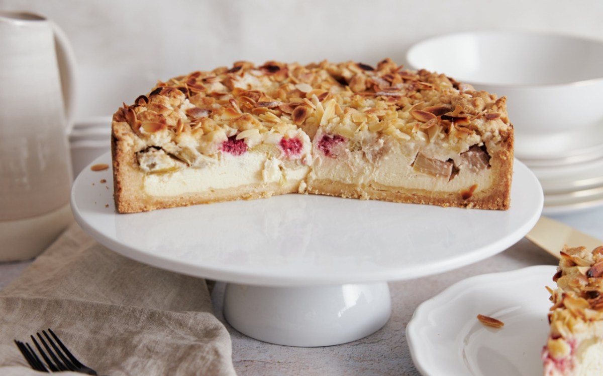 Ein halber Rhabarber-Käsekuchen auf einer Toretenplatte.