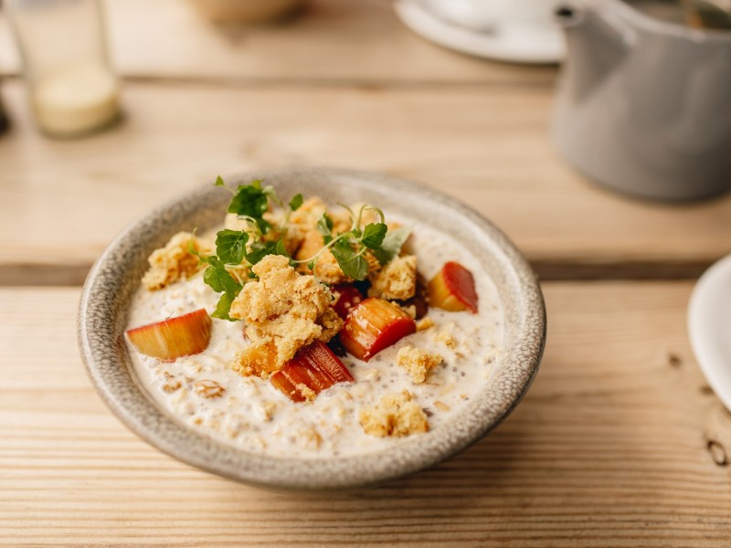 Schale mit Rhabarber-Porridge auf Holztisch.