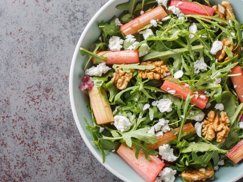 Schale mit Rhabarber-Rucola-Salat auf grauem Untergrund