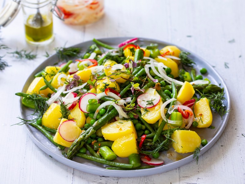 Teller mit Spargel-Kartoffelsalat auf hellem Tisch