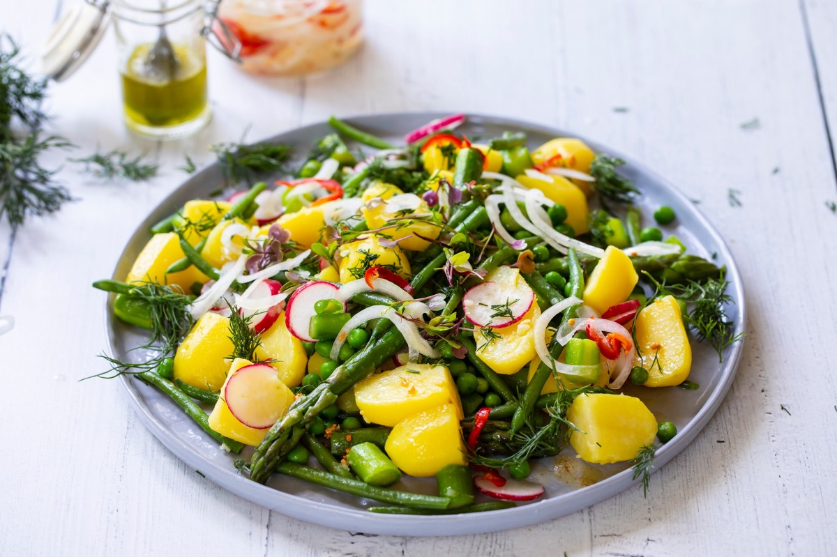 Teller mit Spargel-Kartoffelsalat auf hellem Tisch