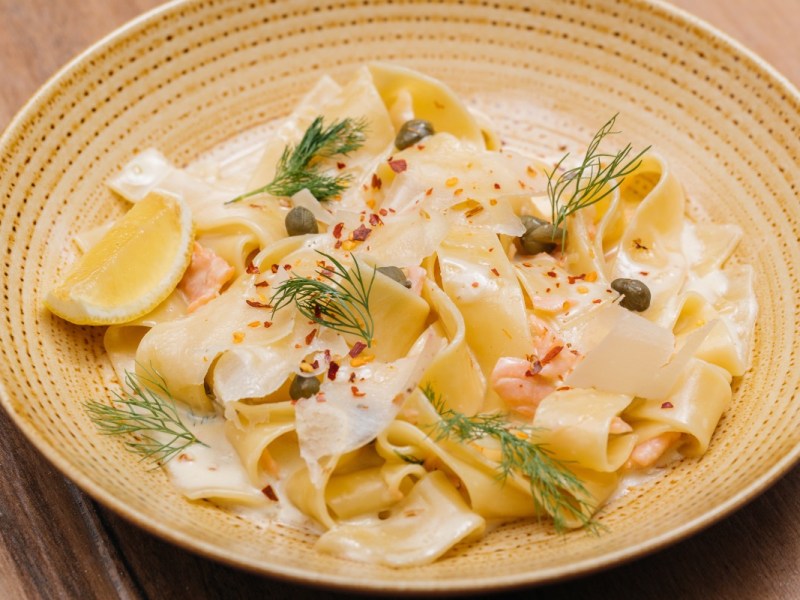 Eine Portion Tagliatelle al Salmone auf einem beigen Teller.