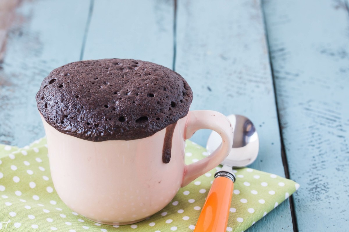 Tassenkuchen aus dem Airfryer, die Tasse steht auf einer grün-weiß gepunkteten Serviette, daneben ein kleiner Löffel.