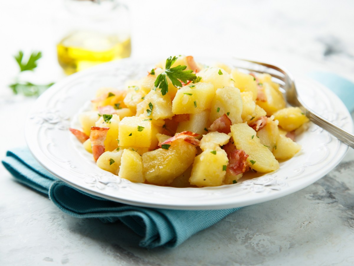 Warmer Kartoffelsalat auf weißem Teller