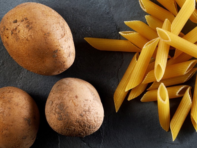 Was ist gesünder, Kartoffeln oder Nudeln: rohe Nudeln liegen neben rohen Kartoffeln.