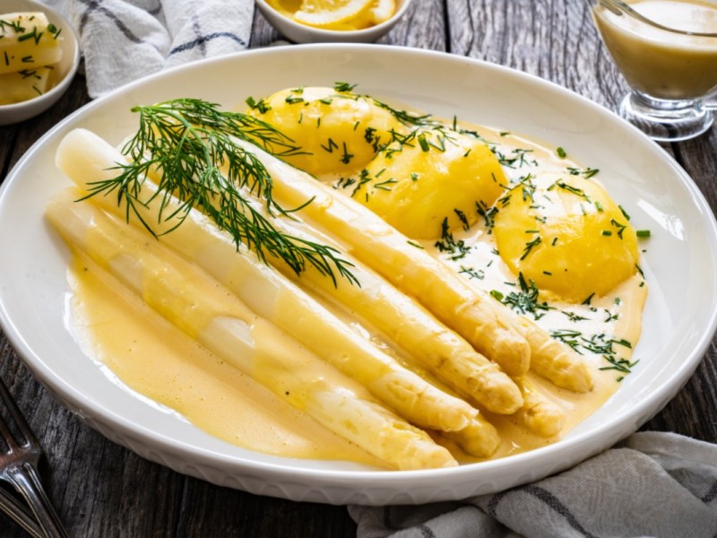 Wie viel Spargel pro Person: eine Portion Spargel mit Sauce hollandaise und Kartoffeln auf einem Teller.