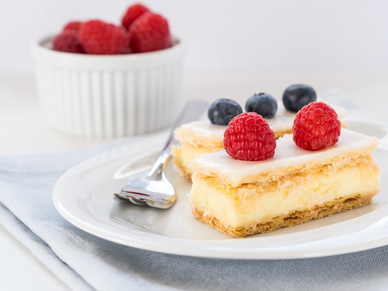 Cremeschnitte mit Beeren dekoriert.