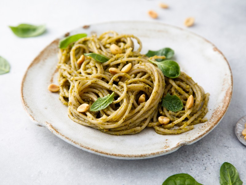 Ein Teller Spaghetti mit Erdnuss-Pesto und Erdnüssen sowie Basilikum, Nahaufnahme.