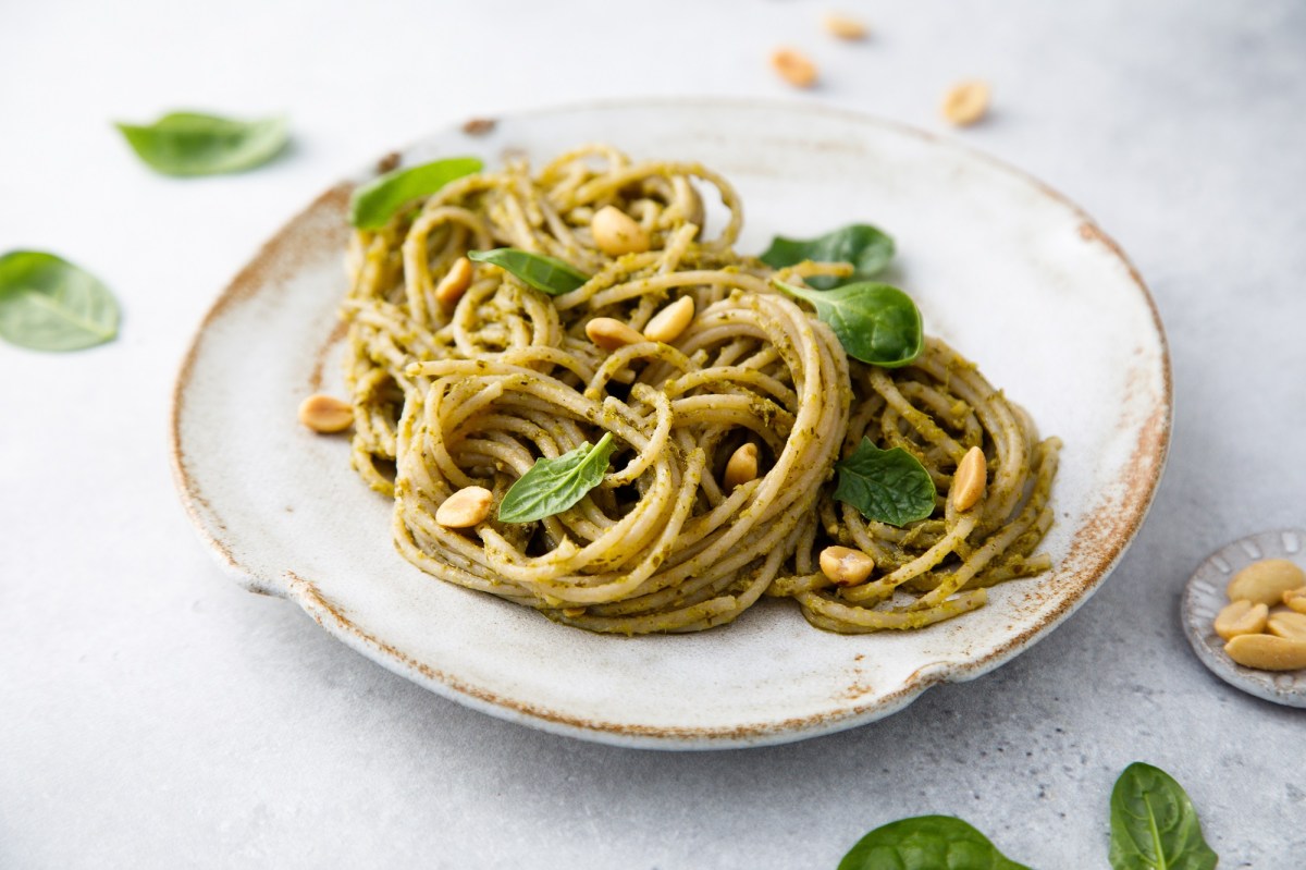 Ein Teller Spaghetti mit Erdnuss-Pesto und Erdnüssen sowie Basilikum, Nahaufnahme.