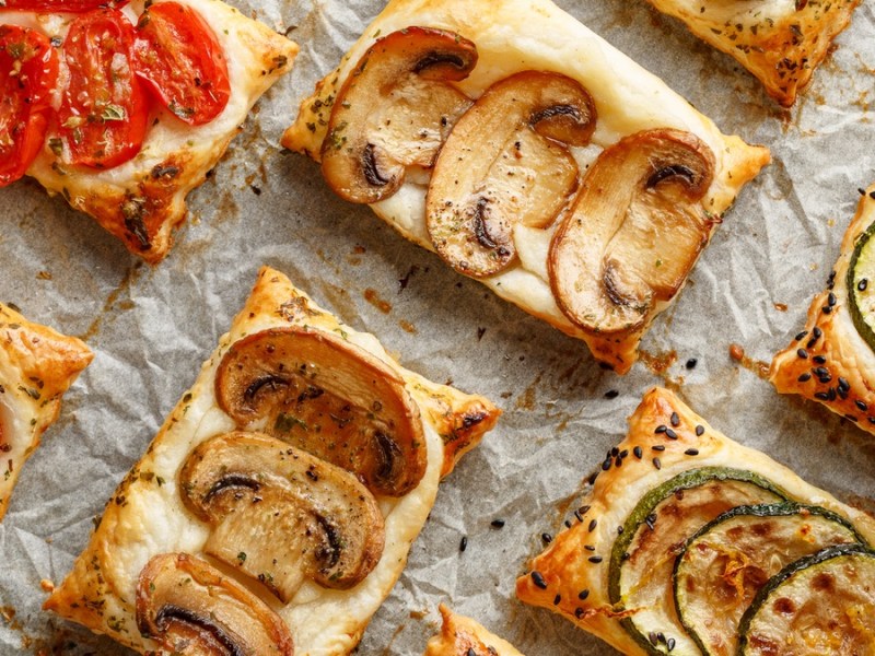 Blätterteig-Schnitten auf Backblech mit Tomate, Pilzen und Zucchini