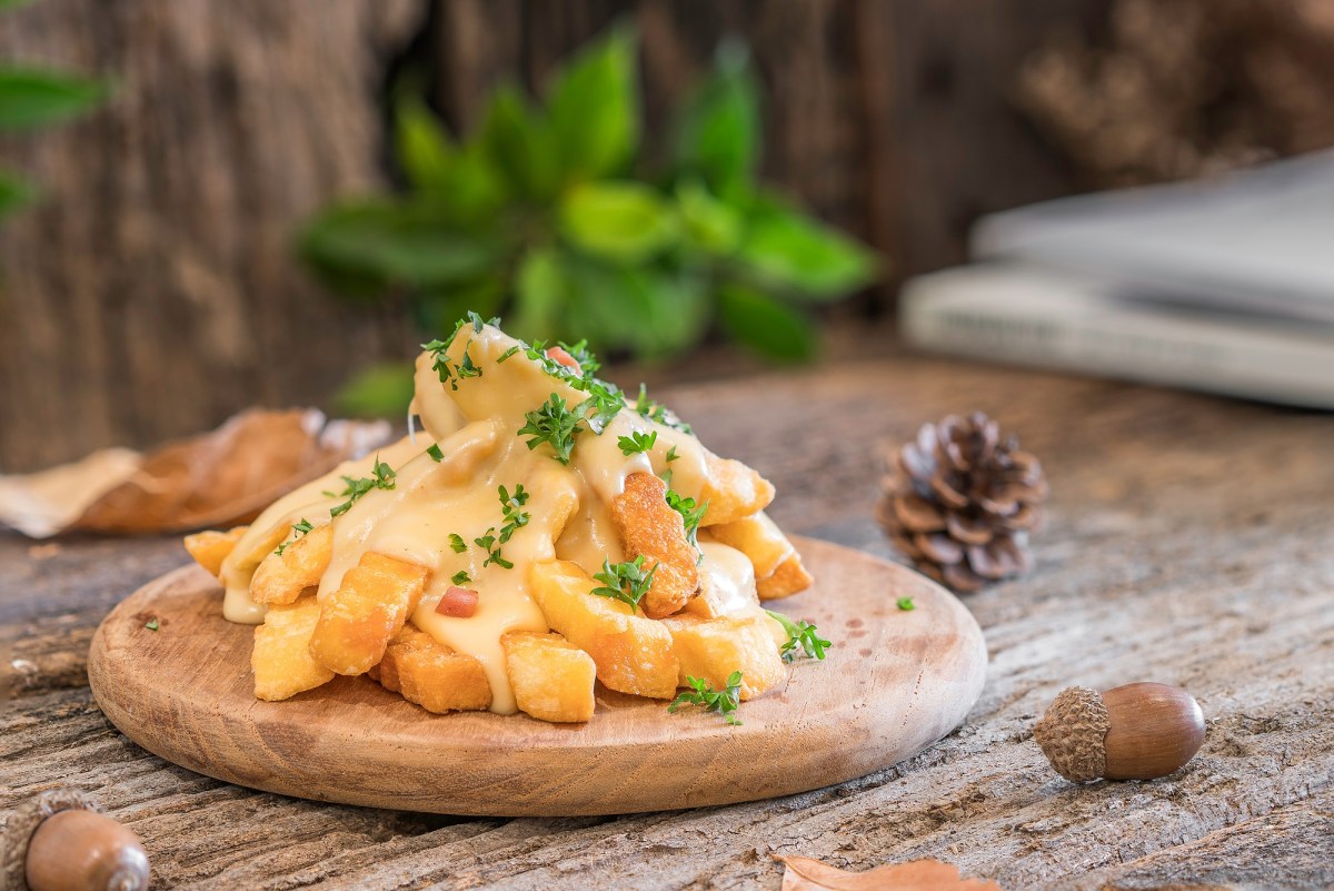 Käse-Pommes auf einem Brett, mit Petersilie bestreut.