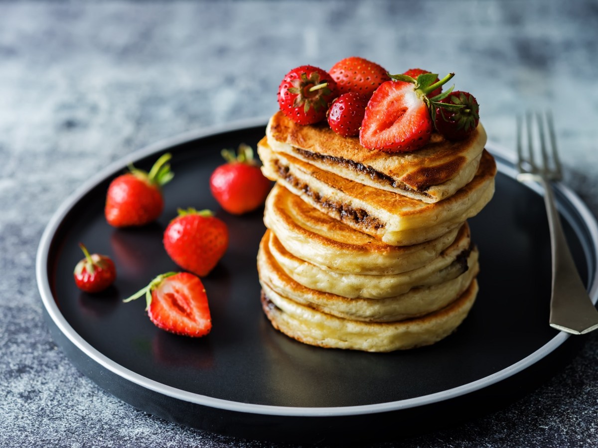 Ein Stapel Pancakes mit Schokoladenfüllung und Erdbeeren.