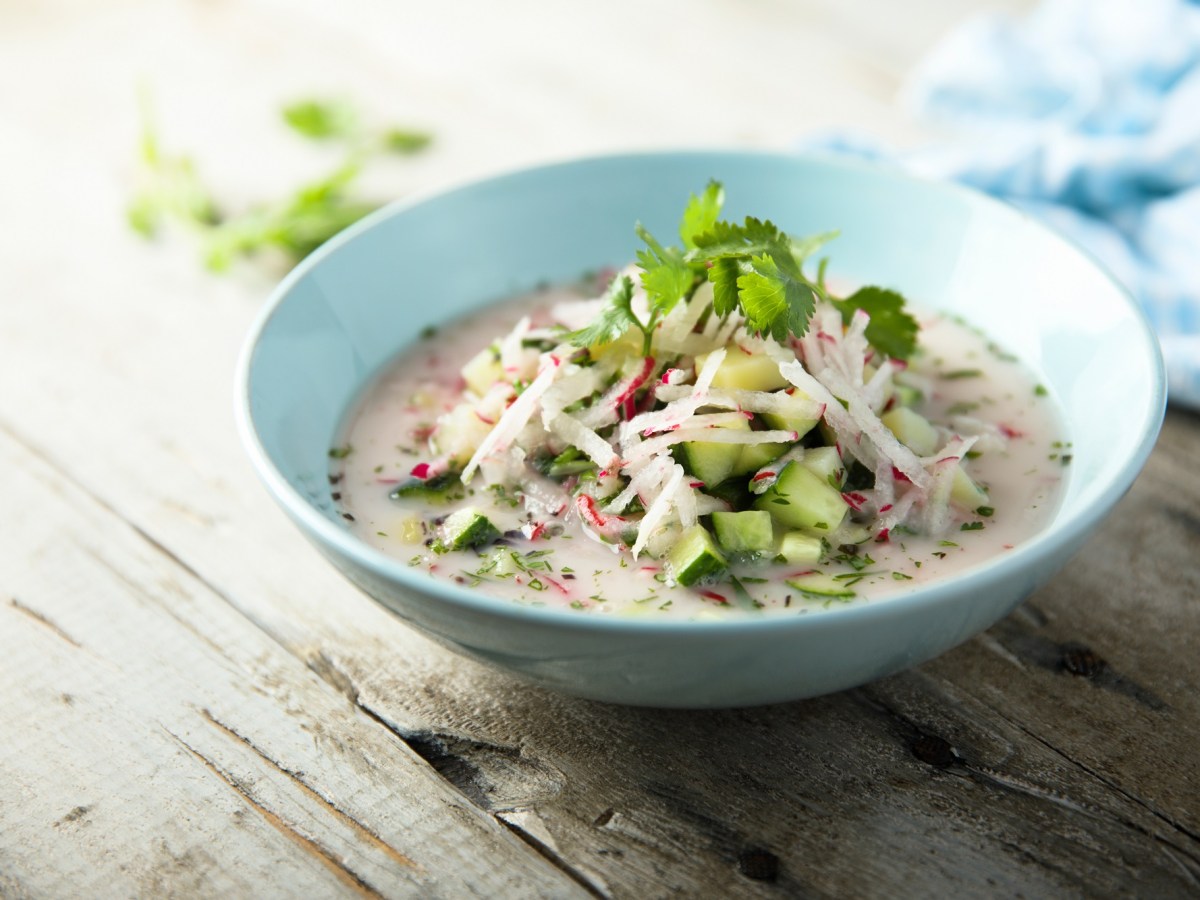 Ein Teller Radieschensuppe mit Frischkäse und Gurke.