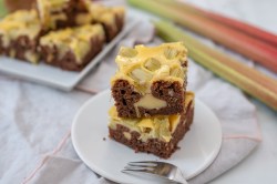 Teller mit Rhabarber-Cheesecake-Brownies, Gabel und Rhabarberstangen