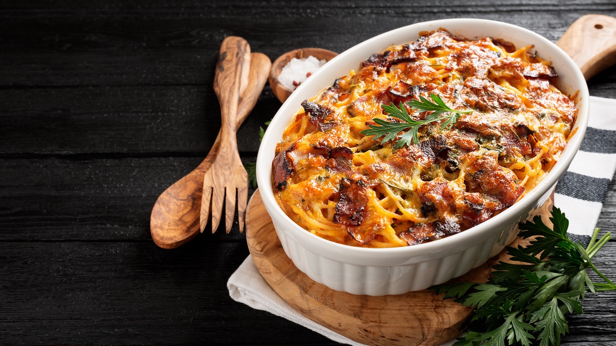 Auflaufform mit Spaghetti-Lasagne auf schwarzem Hintergrund.