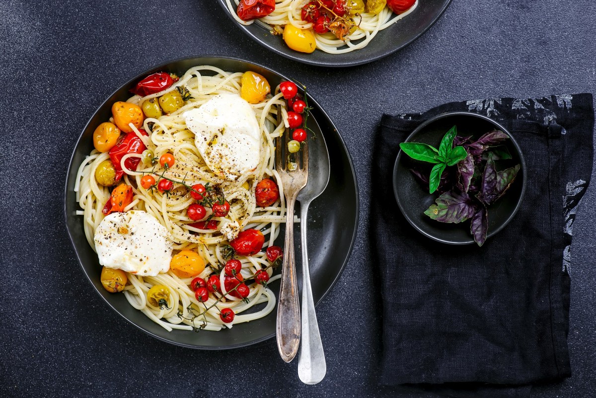 Ein Teller mit Spaghetti mit Burrata und gegrillten Tomaten.