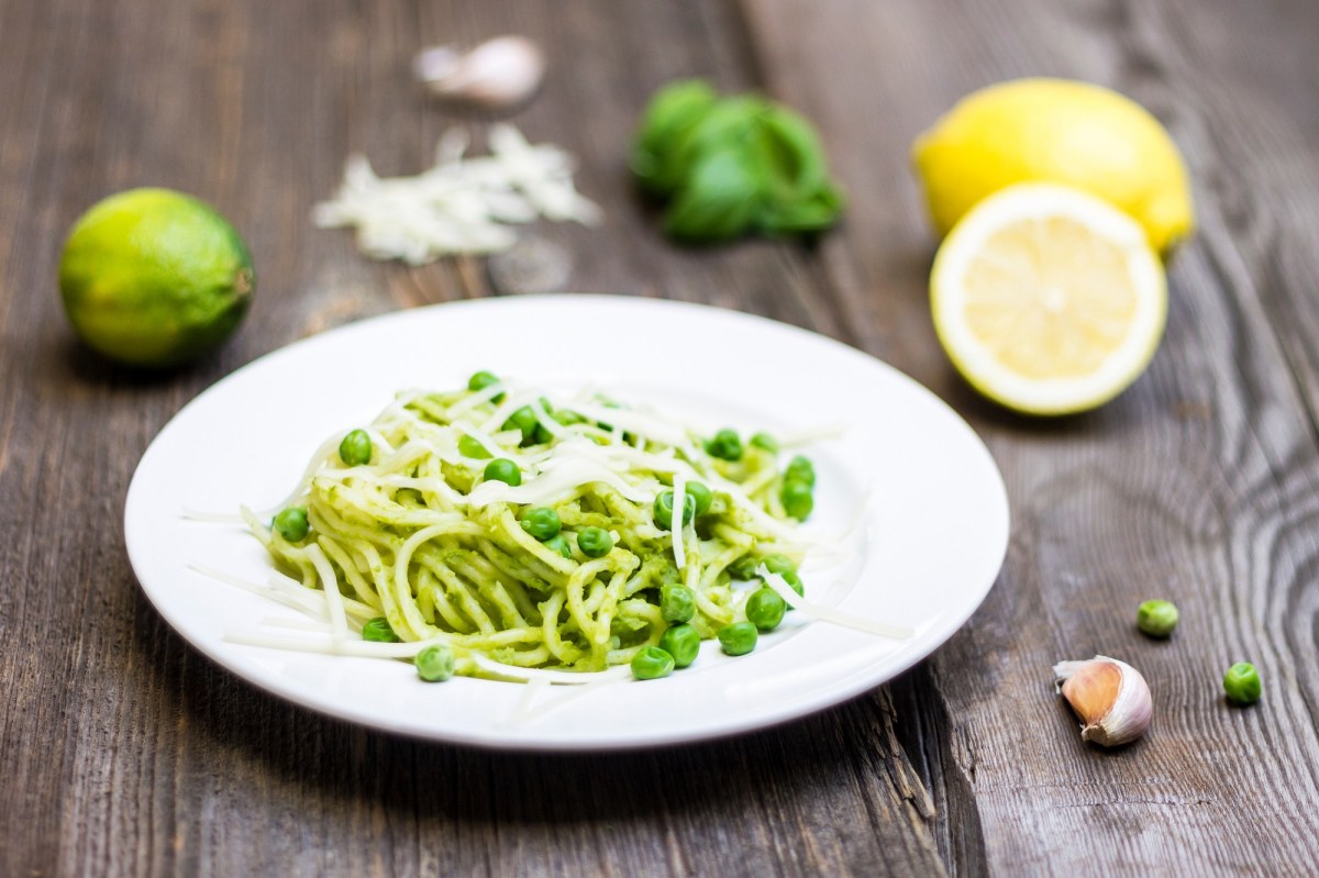 Ein teller Spaghetti e piselli mit Zitrone und Knoblauch daneben.