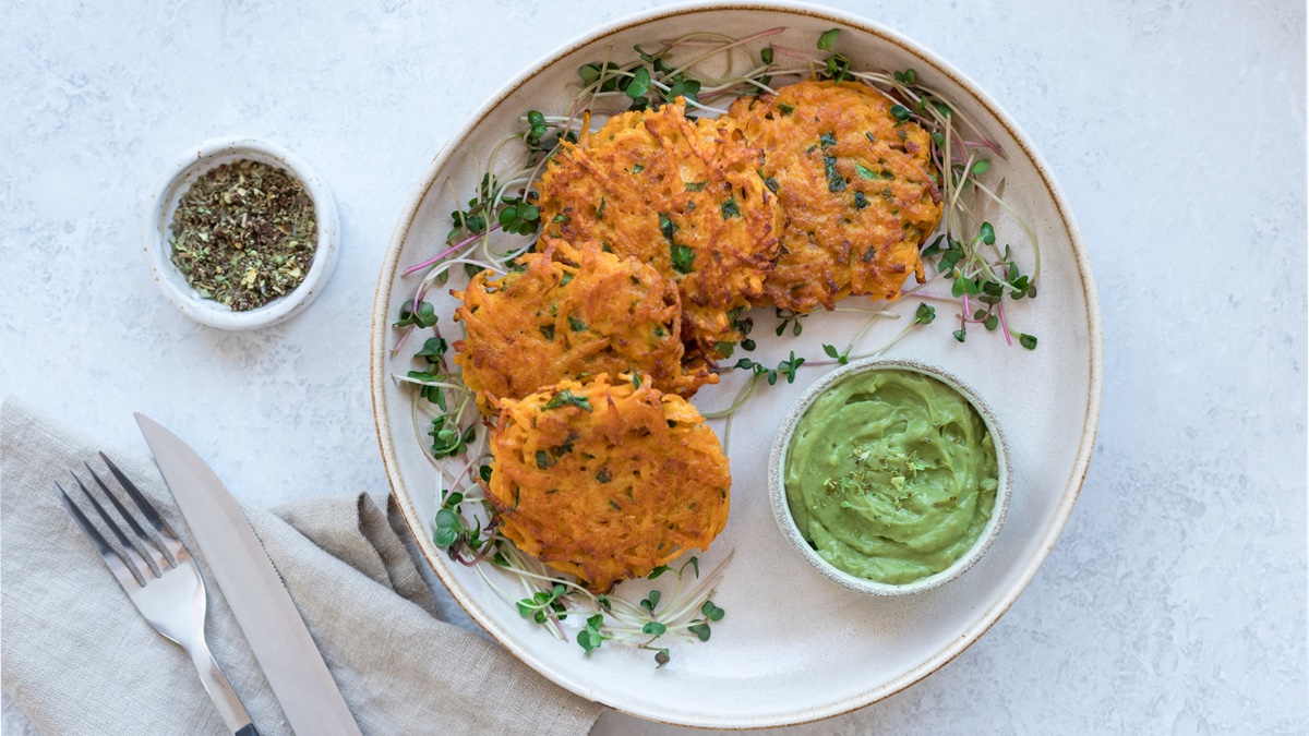 Süßkartoffel-Puffer auf weißem Teller mit grünem Avocado-Dip